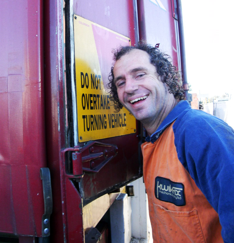 KwikFix Mechanical team member in orange overalls beside a truck